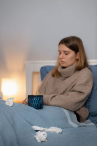 Ill woman with coffee mug sitting at home