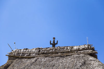 Low angle view of statue against building against clear blue sky