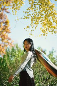 Young woman standing against trees