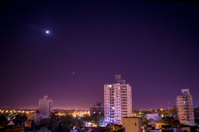 Illuminated buildings in city against sky at night