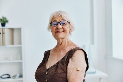 Portrait of smiling woman standing against wall