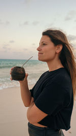 Latina girl drinking argentinian traditional drink called mate in the beach