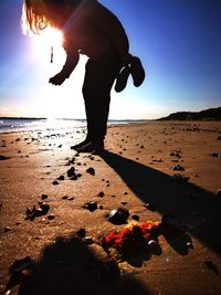 Rear view of man on beach against sky during sunset