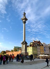 Group of people in front of building against cloudy sky