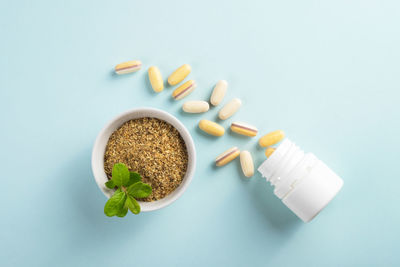 Vitamins and herbal supplements in jars with a green plant.