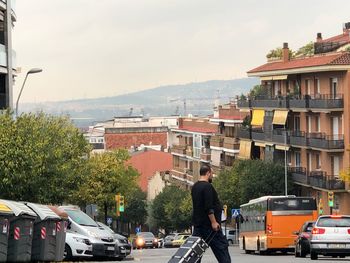 Rear view of man on street in city against sky