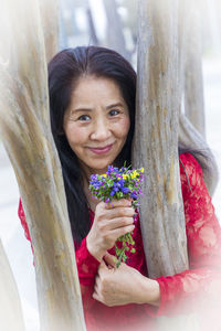 Portrait of a smiling young woman against tree trunk