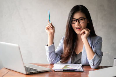 Young woman using phone while sitting on table