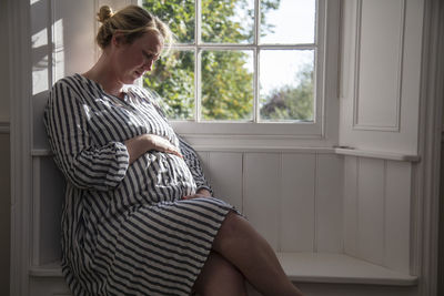 Woman sitting on window at home