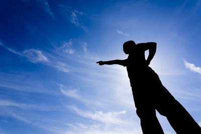 Low angle view of silhouette man against blue sky