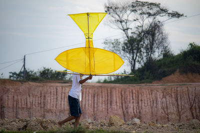 The boy carrying a kite to the field