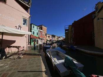 Street amidst buildings against clear blue sky