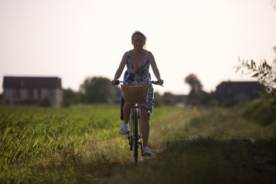 Rear view of man riding bicycle on field