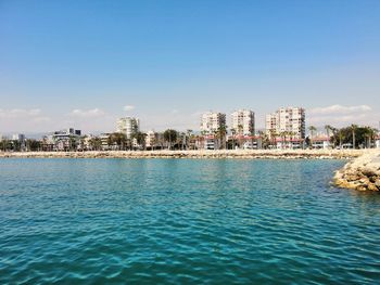 Sea by buildings against clear blue sky