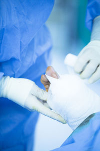 Midsection of surgeon wrapping bandage on patient wound in operating room