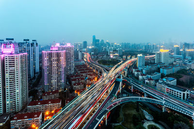 High angle view of illuminated city by buildings against sky