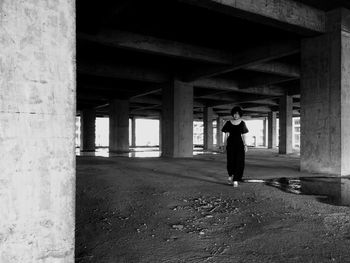 Rear view of woman walking under bridge