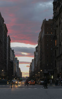 City street and buildings against sky at sunset