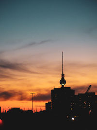 Silhouette of buildings against cloudy sky during sunset