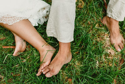 Low section of couple sitting on grass