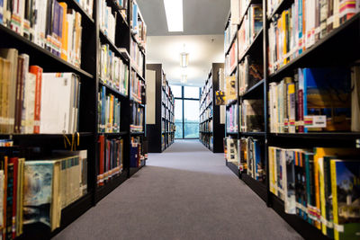Empty corridor amidst bookshelves in library