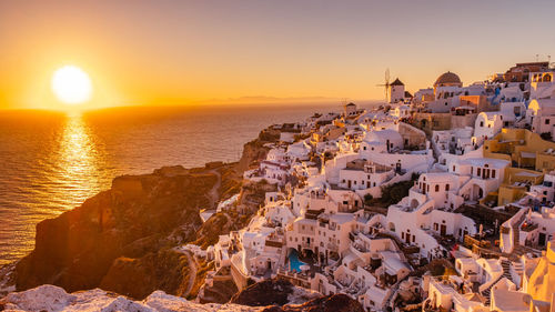 Aerial view of townscape by sea against sky during sunset