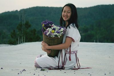 Portrait of girl with flowers sitting on ground