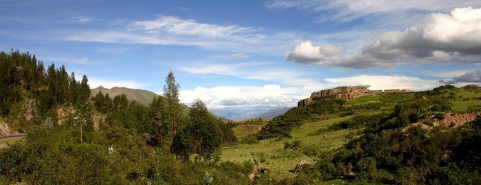 Scenic view of green mountains against cloudy sky