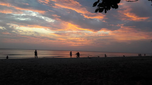 Silhouette people on beach against sky during sunset