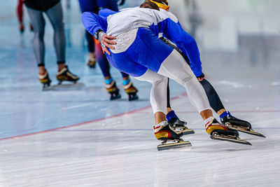 Back men speed skaters running in ice ring