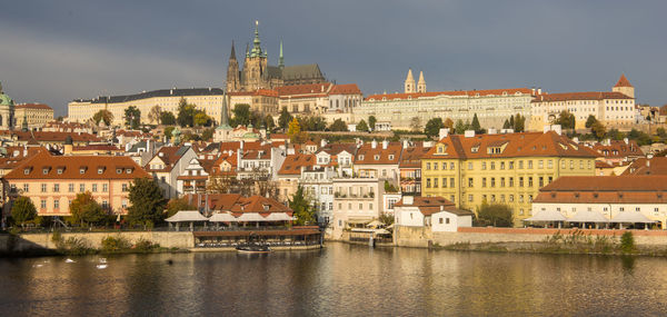 Buildings by river against sky