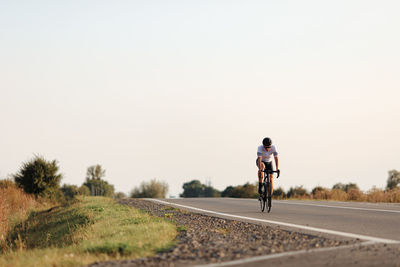Rear view of man riding bicycle on road