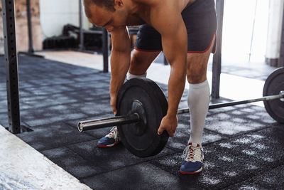 Shirtless man holding barbell at gym