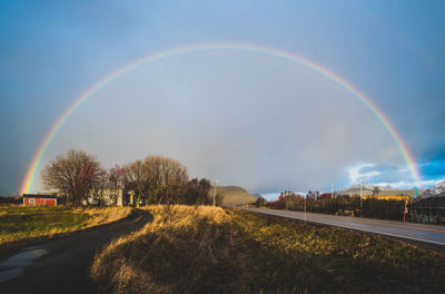 Rainbow over road against sky