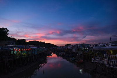 Canal amidst buildings against sky during sunset