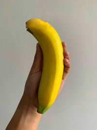 Close-up of hand holding fruit against white background