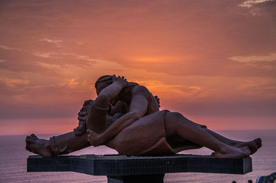 Statue by sea against sky during sunset