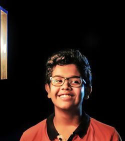 Portrait of young man standing against black background