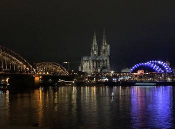 Illuminated bridge over river at night