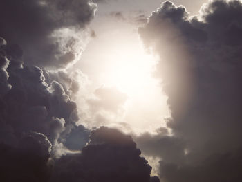 Low angle view of sunlight streaming through clouds