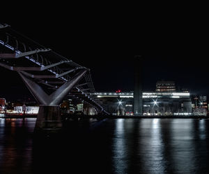 Illuminated bridge over river against sky at night