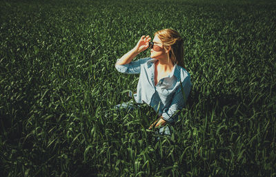 Woman wearing sunglasses while sitting amidst plants