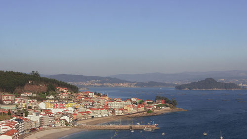 Aerial view of townscape by sea against clear sky