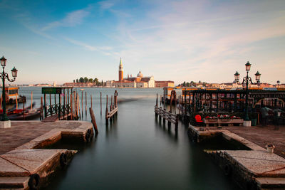 Pier on canal against sky in city