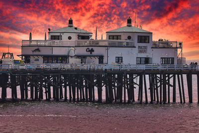 Exterior of building by sea against sky during sunset