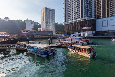 Boats in river against buildings in city