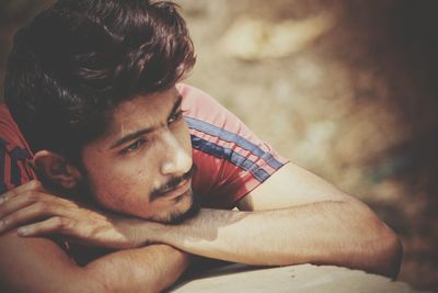 Close-up of thoughtful young man leaning on retaining wall