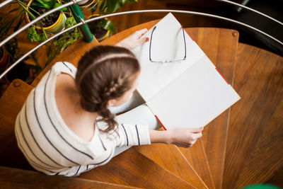 Top view shot of a happy young beautiful woman sitting on the stairs reading a book enjoying