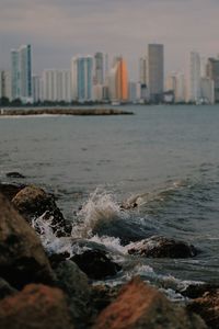 Sea by buildings against sky during sunset