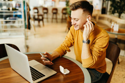 Young man using mobile phone while sitting on table